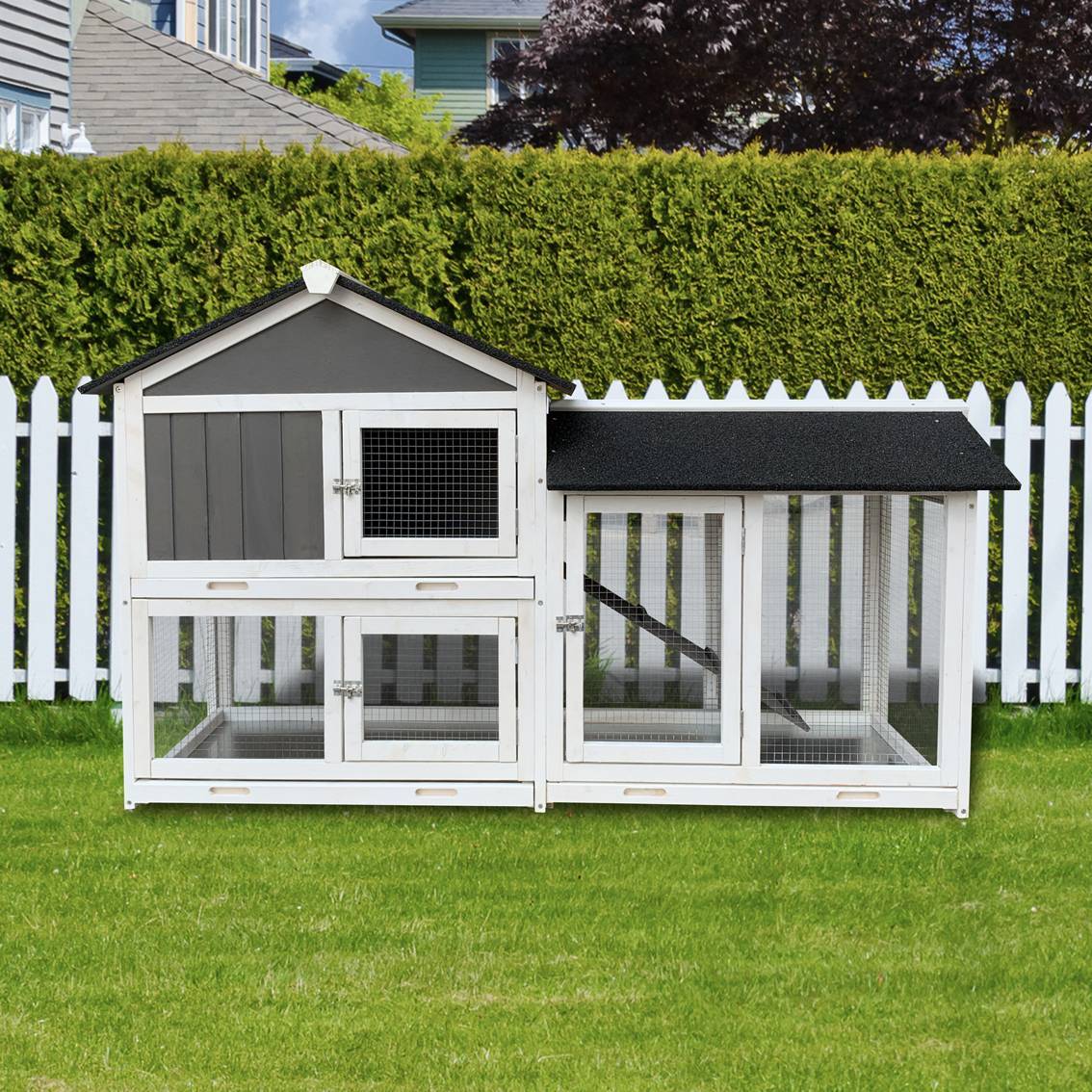 Wooden outdoor rabbit hutch with removable tray and running cage against a green lawn and wooden fence.