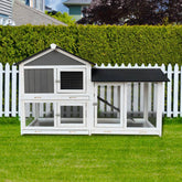 Wooden outdoor rabbit hutch with removable tray and running cage against a green lawn and wooden fence.